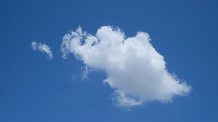 A white cloud of air against a blue sky. Clear day and good weather. The sun is shining brightly. Spring day.