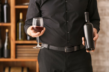 Man with bottle and glass of tasty wine in cellar