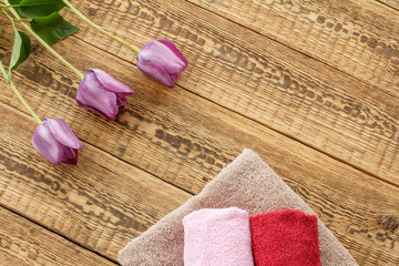 Obraz na płótnie Canvas Towels and lilac tulip flowers on wooden background.