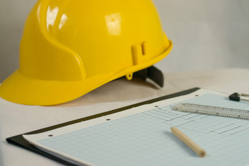 Pencil and drawings on graph paper with ruler and yellow hard safety hat