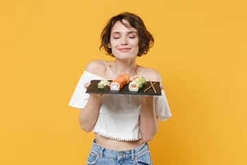 Young brunette woman girl in casual clothes hold in hand makizushi sushi roll served on black plate...