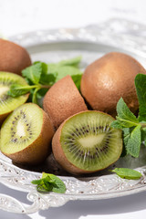 selective focus of tasty kiwi fruits near fresh peppermint on plate