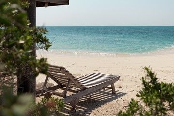 Wooden sunbed on white sand tropical beach. Koh Munnork beach front resort on private island, Rayong province, Thailand.