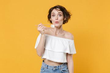 Young brunette woman girl in casual clothes hold in hand sticks chopsticks with makizushi sushi...