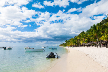 Fototapeta na wymiar Luxury beach in Mauritius. Transparent ocean with boats, beach, palms and blue sky