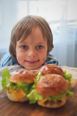 Close up of caucasian boy eating hamburger at barbecue.