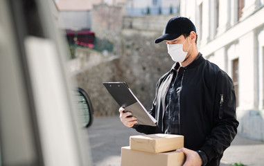 Delivery man courier with face mask delivering parcel box in town. - obrazy, fototapety, plakaty