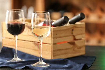 Box with bottles of wine and glasses in cellar