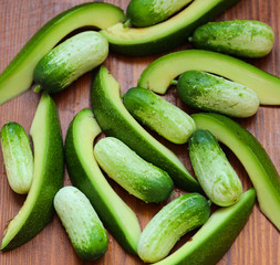 small cucumbers and avocado slices on a wooden table