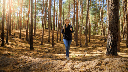 Young woman with big tourists bag hiking on the path through pine forest