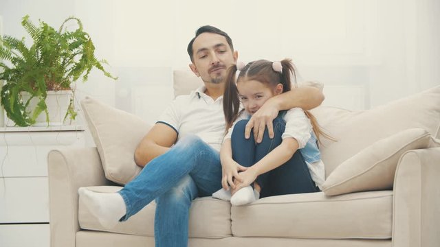 Nice daddy hugging his beautiful daughter on a coach in 4k slowmotion video.
