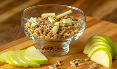 Oatmeal in a glass bowl, next to it is a sliced apple. Selective focus