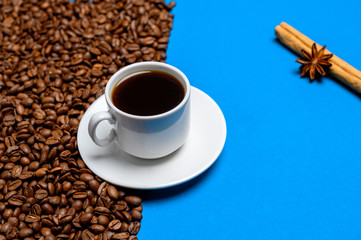 coffee beans, cup with coffee with cinnamon on a blue background