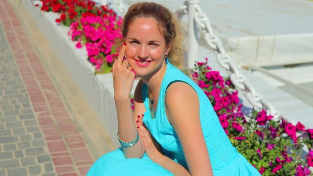 young blonde with a lovely smile in a turquoise dress on a background of vivid colors 4K video