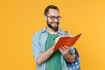 Obraz na płótnie Canvas Smiling young man student in casual clothes glasses with backpack isolated on yellow background. Education in high school university college concept. Mock up copy space. Writing notes in notebook.
