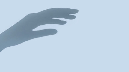 Hand shadow on light blue background with copy space. Touching. Reach out