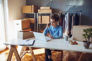 Young smiling entrepreneur working on laptop at her workplace. Confident online business owner...