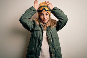 Young brunette skier woman wearing snow clothes and ski goggles over white background Doing bunny ears gesture with hands palms looking cynical and skeptical. Easter rabbit concept.