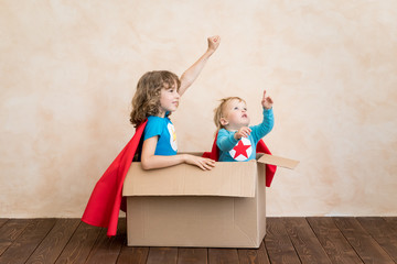Superheroes children playing in cardboard box