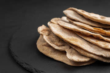Whole-wheat tortillas on a black slate Board in close-up
