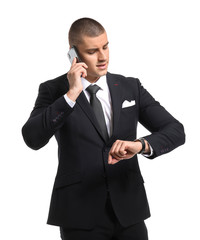 Handsome young man in elegant suit talking by phone on white background