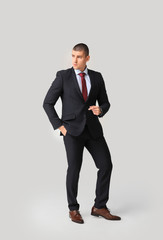 Handsome young man in elegant suit on light background