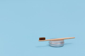 Bamboo brush and metal jar on a blue pastel background. Zero waste concept with copy space.
