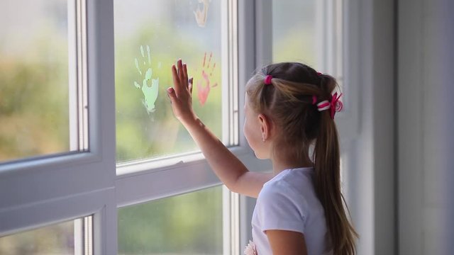  Children girl draw with palms on the window. Painted hands leave a mark on the glass. Quarantine. Stay home. Flash mob society community on self-isolation quarantine pandemic coronavirus.
