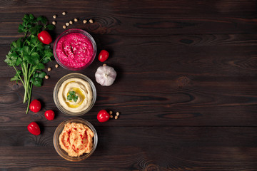 Colorful hummus bowls with crispy bread on wooden table