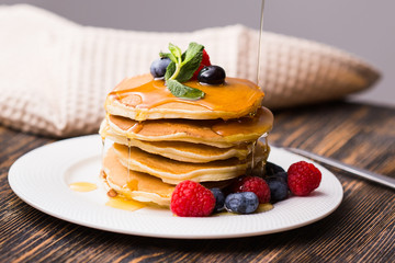 Close-up of pouring maple syrup on stack of pancakes.