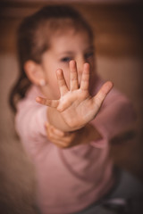 Cute child girl make symbol at her hand saying stop. Human rights or refugee day concept. Child palm saying stop.