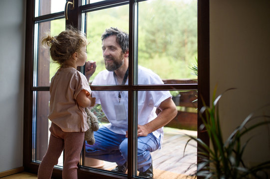 Doctor coming to see family in isolation, window glass separating them.