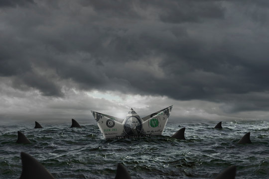 Boat made with a dollar bill in the middle of a marine storm and surrounded by sharks