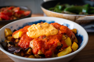 Patatas Bravas in a bowl, surrounded by healthy vegetarian foods.