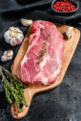 Raw marble pork steak on a wooden chopping Board. Organic meat. Black background. Top view