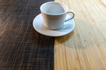 Empty white cup and saucer stands on a two-color background on the table.