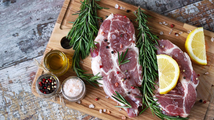 Raw meat steaks on a cutting board. Fresh meat with rosemary and spices. Pork chops. Selective...