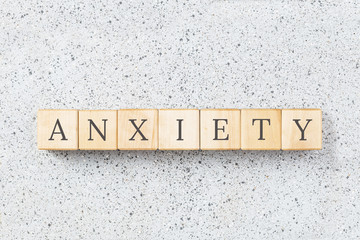 Anxiety word made with wooden building blocks on grey cork background. Uncertainty and panic concept. Minimal