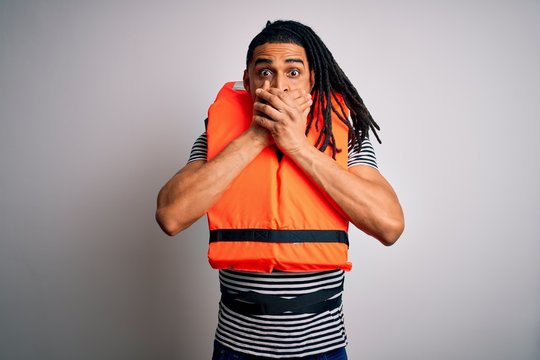 Young african american afro man with dreadlocks wearing orange lifejacket shocked covering mouth with hands for mistake. Secret concept.