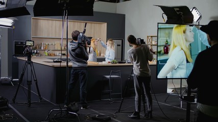 WIDE Behind the scenes of studio set, makeup artist make corrections during shooting television...