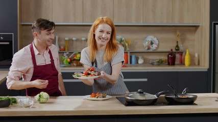 Cooking show hosts chefs, male and female, showing cooked dish into camera. Morning TV cooking...