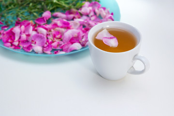 Homemade herbal tea in a white cup. Tea rose petals and thyme - ingredients for hot healthy drink 