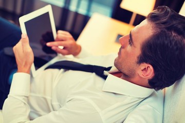 Attractive businessman using tablet PC in bedroom