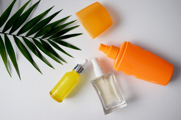 Summer cosmetic set with orange bottle sunscreen ads and palm leaf top view space for text