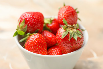 Bowl with ripe strawberry on table, closeup