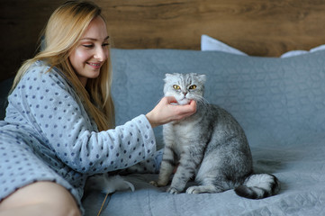 Beautiful young woman with cute cat on a bed