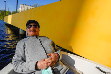 Fototapeta na wymiar Stockholm, Sweden May 24, 2020 An 82 year old man sits in a little boat on a sunny day.