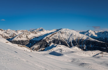 Fototapeta na wymiar January 2020 Sillian, Austria: snowy ski run on the foreground, blue sky on the background