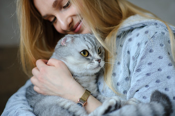 Beautiful young woman with cute cat on a bed