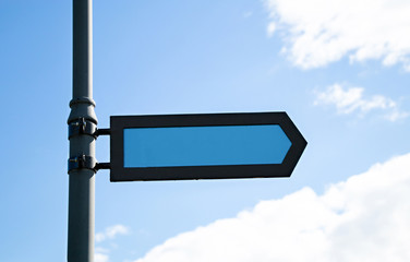 Empty blue pointer on metal pole indicating to the left against the sky